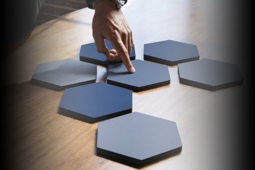 Hands pointing to connected hexagon cut out paper